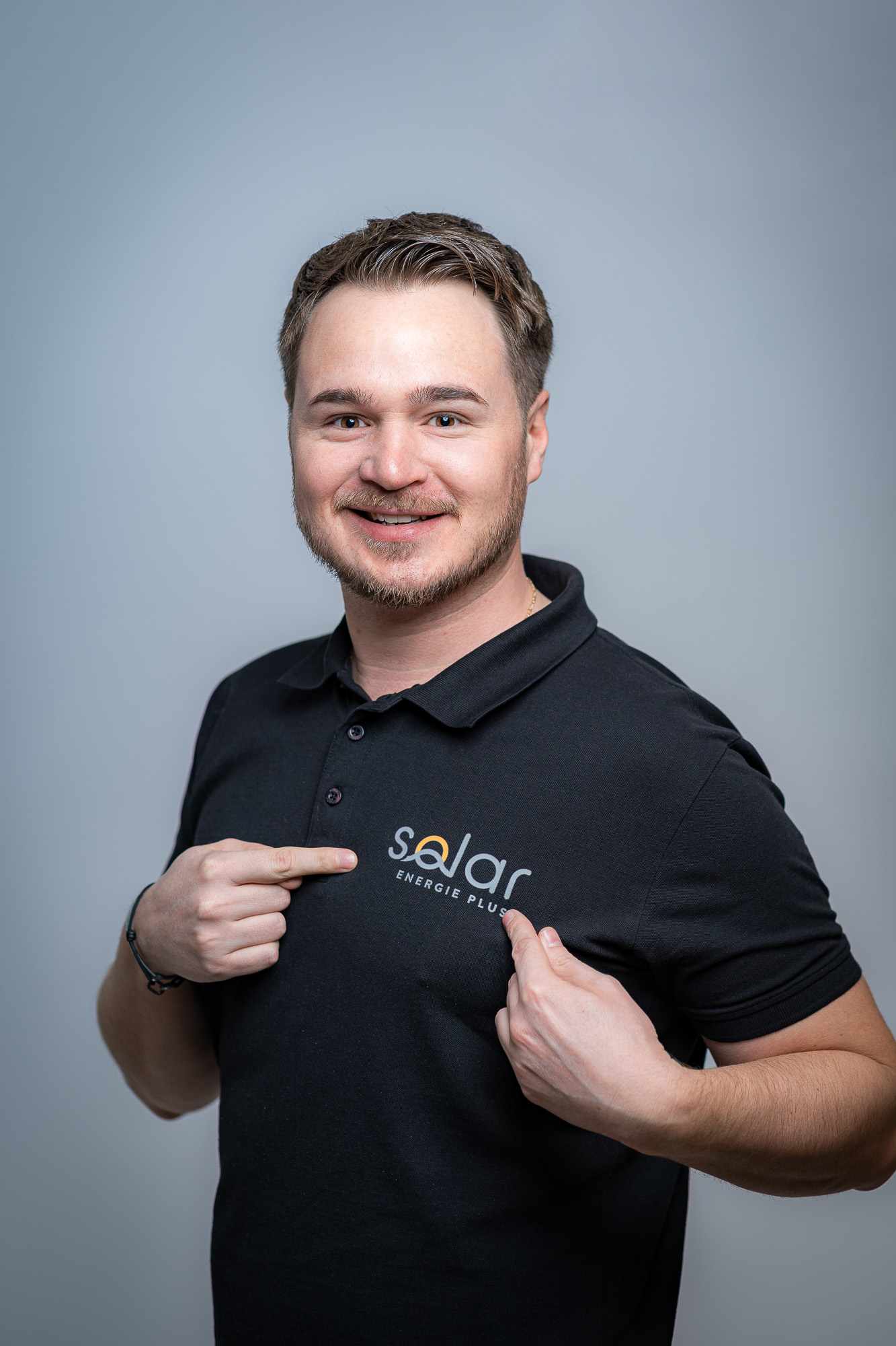 Stefan Kurz zeigt auf das Solar Energie Plus Logo auf seinem Polo
