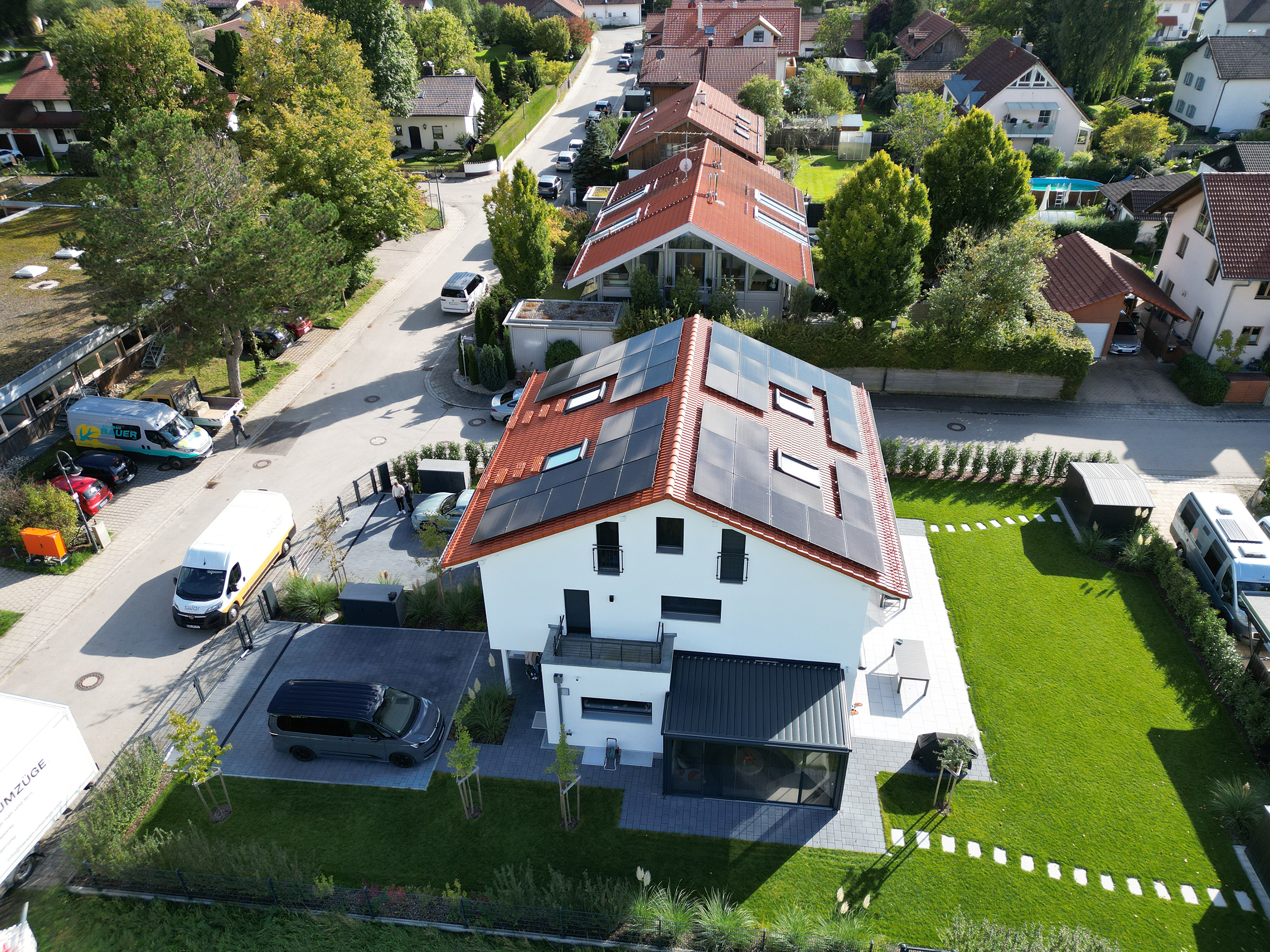 Service_Beratung Eine Photovoltaikanlage auf dem Dach eines modernen Wohnhauses. Die umliegenden Wohngebäude und Straßen prägen die Nachbarschaft.